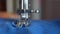 Sewing machine in operation. Close up of a sewing machine sewing blue fabric