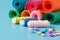 sewing supplies, colored threads, colored pieces of cloth, needles, tailors scissors on blue background