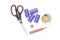 Sewing supplies and tools, medium purple threads, yellow tape with black numbers, big scissors, metal thimblele