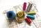 Sewing supplies on a white wooden table: sewing thread, scissors, a large spool of thread, pieces of cloth, needles,centimeter