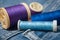 sewing thread spool bobbin on blue jeans background