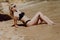 Sexual blonde girl take sunbath on the beach. happy female with black swimwear, enjoying summer holidays