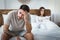 Sexual dysfunction. Husband holds his head, upset wife on bed