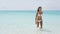 Sexy Asian bikini woman relaxing on beach walking out of turquoise ocean water