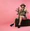 sexy Asian woman in military uniform with an automatic rifle sits on an ammunition crate