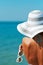 Sexy back of a beautiful woman in bikini, creative hat and sunglasses on sea background