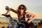 Sexy blonde woman in sunglasses smiling and grimacing while sitting on the motorbike. Bright emotions on vacation