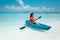 Sexy brunette paddling a kayak. Woman exploring calm tropical bay. Maldives. Sport, recreation. Summer water sport, adventure