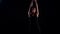 Sexy brunette woman is dancing in black background, athletic and flexible body