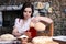 Sexy Caucasian Girl in Rural Decorated Dress Pouring Milk in Front of Food Ingredients for Bread Baking in Countryside Environment