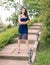 Sexy Caucasian Woman Outdoors, on the Stairs of a Garden, in a Lace Blue Dress, with Long Curly Hair and Dominant Attitude