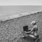 Sexy freelance girl in an erotic swimsuit working at a computer on the ocean, free work not tied to a place of residence