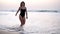 Sexy girl in a bathing black suit walks over a sandy beach at the ocean - gorgeous long haired caucasian girl walks