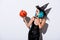 Sexy girl in black witch Halloween costume with blue hair blowing kiss to spooky carved pumpkin