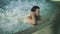 Sexy guy relaxing in pool at spa hotel. Man touching wet hair in jacuzzi at spa
