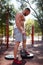 Sexy, hot muscular sportsman doing exercises in the park. A strong boy on a natural background. Sports concept.