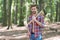 Sexy lumberjack man in open plaid shirt with jeans carry large splitting axe in summer forest natural landscape, wood