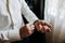 A sexy male businessman fastens a cufflink on his wrist watch, the cuff of the sleeve of a luxurious white shirt