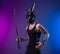 a sexy man in a demon mask and leather bdsm straps holds a katana sword in his hand on a neon background