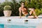 Sexy muscular man in swim trunks relax and posing near swimming pool outdoors