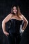 Sexy plus size model in black corset, fat woman with big natural breasts on dark background, body positive concept