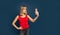 Sexy slim blonde womanin red t-shirt on a blue studio background making selfie with smartphone. Copyspace