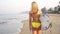 A sexy surfer woman in a swimsuit is walking along the beach with a surfboard