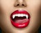 Sexy Vampire Woman`s red bloody lips close-up. Vampire girl licking fangs with tongue. Fashion Glamour Halloween