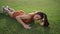 Sexy woman lying on the green grass. Fitness woman floor exercise moves hands.