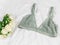 Sexy women`s underwear and flowers on the bed. Green bra, lace lingerie on a white bedsheets. Beauty blogger concept. Top view,