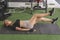 A sexy young asian woman does flutter kicks while lying on a black mat at the gym. Working out abs and core