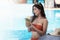 Sexy young asian woman in swimsuits in summer. beautiful woman in orange bikini with hat and tropical drink in swimming pool