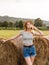 Sexy young blonde girl on haystack roll on harvested wheat field in the summer. Selective focus.