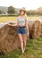 Sexy young blonde girl on haystack roll on harvested wheat field in the summer. Selective focus. full body fashion portrait of