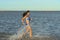 A sexy young brunette woman or girl wearing a bikini running through the surf on a deserted tropical beach with a blue sky. Young