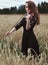 Sexy young woman in a black dress enthusiastically playing the violin in a wheat field in a strong wind