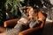 A sexy young woman in a business suit rests in the armchair at the office with shadow from plants on the wall behind her