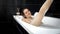 Sexy young woman lying in bath and washing leg with sponge. Female hygiene, relaxing in bathroom, beauty and health