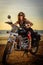 A sexy young woman in sunglasses sits on a black chrome motorbike. Hipster girl on a motorcycle against the sunset. Vertical
