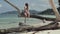 Seychelles. Praslin Island. Pretty slim attractive young woman sitting on the tree trunk at the water on the beach