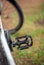 Shabby bicycle pedal on a blurred background of the wheel and grass