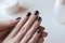 Shabby dark blue manicure. Threadbare nail polish. Woman hands on white table