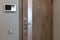 Shabby design entrance door in a modern apartment hallway, video intercom device on the wall. Neutral tones. Security concept,