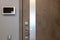 Shabby design entrance door in a modern apartment hallway, video intercom device on the wall. Neutral tones. Security concept,