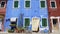 Shabby facade of blue colored house decorated with nice flower pots, poverty