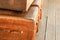 Shabby old brown big suitcase, a stack of luggage stands on a wooden background