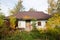 Shabby and old country house, made of wood and clay, against cloudy October sky, open yard