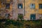 Shabby overgrown grungy wall, broken windows, abandoned house