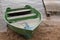 Shabby wooden boat painted green with two benches for rowing moored by rope at small board pier on shore of a bay of lake