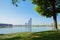 Shaded lakeside lawn in summer morning with modern buildings across lake